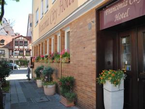 um edifício de tijolos com vasos de plantas ao lado em Franconia City Hotel em Nurembergue