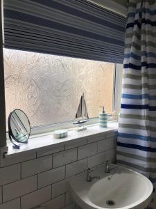 ein Badezimmer mit Waschbecken und einem Fenster mit Spiegel in der Unterkunft 34 Brunton Street Serviced Accommodation in Darlington