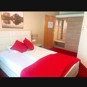 una camera da letto con un grande letto bianco con cuscini rossi di Hotel Aragia a Klagenfurt
