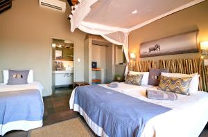 a bedroom with two beds with blue sheets at Twyfelfontein Country Lodge in Twyfelfontein +30 photos