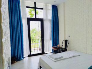 a bedroom with a bed and a window with blue curtains at Dolphin Home in Dong Hoi +69 photos