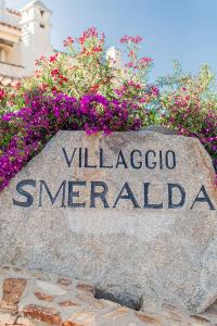 una roccia con le parole villaggio smeraldo davanti ai fiori di Villaggio Smeralda by Sardegna Smeralda Suite a Porto Rotondo
