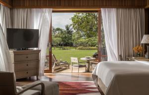 a bedroom with a bed and a television and a patio at Four Seasons Resort Langkawi in Tanjung Rhu