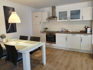 ジンゲンにあるFerienwohnung Schwartzの白いキャビネット、テーブルと椅子付きのキッチンが備わります。