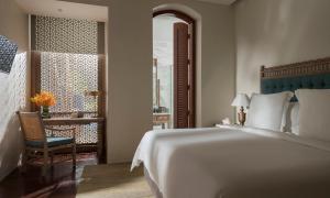 a bedroom with a bed and a chair and a desk at Four Seasons Resort Langkawi in Tanjung Rhu