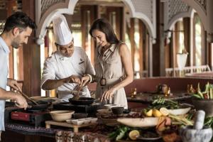 a man and a woman preparing food in a kitchen at Four Seasons Resort Langkawi in Tanjung Rhu