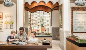 a man and two children sitting at a table in a restaurant at Four Seasons Resort Langkawi in Tanjung Rhu