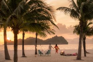 a man and woman walking on a beach with palm trees at Four Seasons Resort Langkawi in Tanjung Rhu