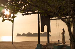 a woman standing on the beach at sunset at Four Seasons Resort Langkawi in Tanjung Rhu