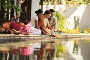 a group of people sitting next to a pool of water at Four Seasons Resort Langkawi in Tanjung Rhu