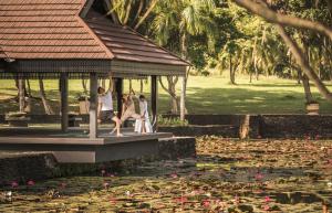 three people sitting in a gazebo over a pond of lilies at Four Seasons Resort Langkawi in Tanjung Rhu