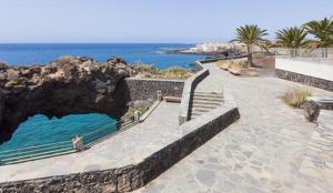 a walkway next to the ocean with people sitting on benches at Sea Mountain in Atlántico in Costa Del Silencio