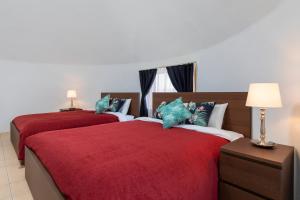 two beds in a bedroom with red sheets and blue pillows at Uruma Dome Okinawa in Uruma