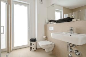 uma casa de banho com um lavatório, um WC e um espelho. em Lunas Appartements Essen em Essen