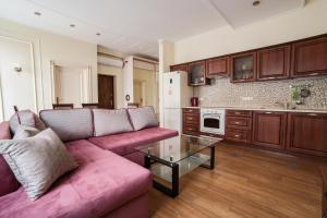 a living room with a pink couch and a kitchen at Апартаменти з балконом (2 ізольовані спальні) в центрі Львова in Lviv
