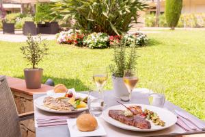 uma mesa com dois pratos de comida e copos de vinho em The Originals Boutique, Hôtel Les Strélitzias em Juan-les-Pins