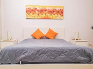 a bed with orange pillows and a painting on the wall at Casaulente in Alcamo