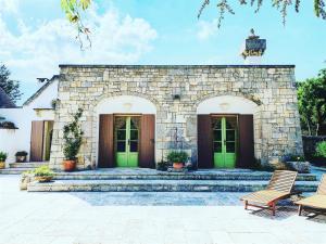 a stone house with green doors and two chairs at Trulli d'Itria in Martina Franca