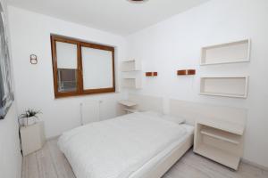 - une chambre blanche avec un lit et une fenêtre dans l'établissement Apartament Słoneczny 10, à Carolinensiel