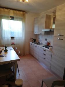 uma cozinha com armários brancos, uma mesa e uma sala de jantar em Villino Verde Pomodoro em Arezzo