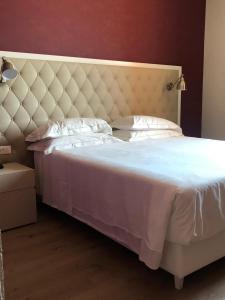 1 dormitorio con cama blanca y cabecero grande en Zanhotel Regina, en Bolonia