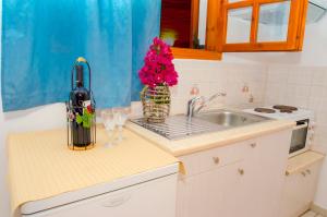 a kitchen with a bottle of wine and flowers on a counter at Palaios Rooms in Plaka Milou