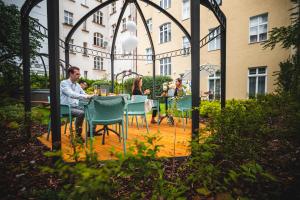 a group of people sitting at a table in a garden at Garden Suites Residence by TKC in Prague