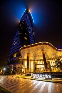 a large building at night with a tall building at Auto City Ruili Hotel in Jiading