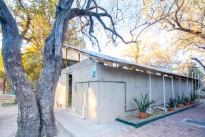 a small white building with a tree next to it at Sitatunga Campsite Maun in Maun