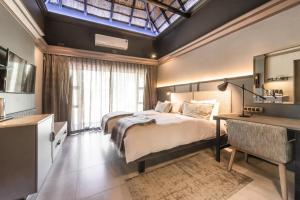 1 dormitorio con 2 camas, escritorio y lavamanos en Mokuti Etosha, en Namutoni