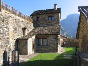 an old stone building with a grass yard in front at Apartamentos Russell in Torla-Ordesa