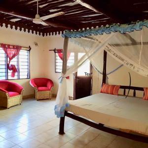 a bedroom with a canopy bed and two chairs at A wonderful Beach property in Diani Beach Kenya.a dream holiday place. in Mombasa