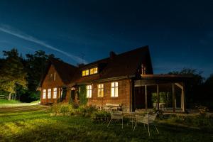 ein großes Holzhaus mit nachts eingeschaltetem Licht in der Unterkunft Dom Gościnny Stara Szkoła in Wysoka Wieś