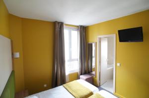 a room with a television and a window at Hôtel De France in Boulogne-Billancourt