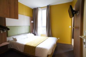 a bedroom with a bed with yellow walls and a window at Hôtel De France in Boulogne-Billancourt