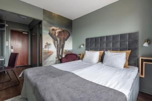 a bedroom with a large bed with an elephant painting on the wall at Quality Hotel Galaxen in Borlänge