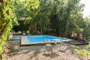 a swimming pool with chairs and a table in a yard at Forest House casinha do Carvalhal in Vila Nova de Cerveira