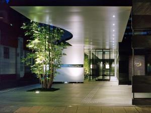 Richmond Hotel Kagoshima Tenmonkan في كاجوشيما: شجرة أمام مبنى في الليل