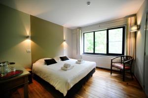 a bedroom with a bed and a chair and a window at B&B De Meren in Aarschot