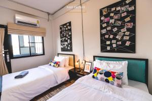 a bedroom with two beds and a wall with pictures at Post Factory Bed & Breakfast in Bangkok