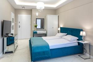 a bedroom with a blue bed and a television at Apartamenty Prestiż 93 in Koszalin