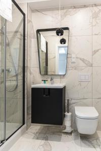 a bathroom with a sink and a toilet and a mirror at Apartamenty Prestiż 93 in Koszalin
