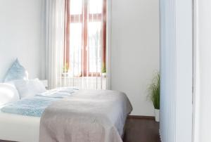 a white bedroom with a bed and a window at Wohnung in TOP-Lage - Direkt am Bahnhof in Bad Wimpfen