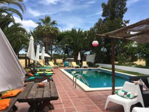 a swimming pool with chairs and a table and a wooden tablektop at Quinta do Xarrama in Évora