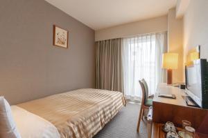 a hotel room with a bed and a desk with a television at Hotel Gimmond Kyoto in Kyoto