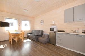 a kitchen and living room with a couch and a table at Domki PoZdrowie in Rusinowo