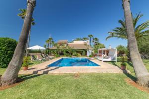 a villa with a swimming pool and palm trees at Can Picafort - 232562 in Santa Margalida
