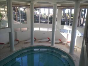 a swimming pool in a building with columns and windows at Hotel Terme Marine Leopoldo II TERME & SPA in Marina di Grosseto