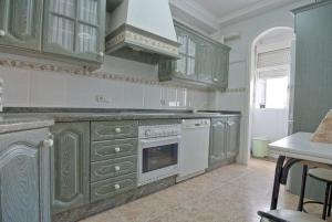 cocina con armarios verdes y fogones horno superior en Habitación en casa compartida, en Huelva