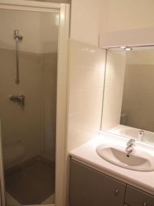 een badkamer met een wastafel, een douche en een spiegel bij Les Soleiades in La Londe-les-Maures